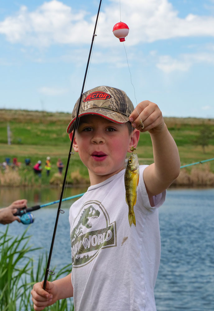 Kid holding up a perch by that was caught