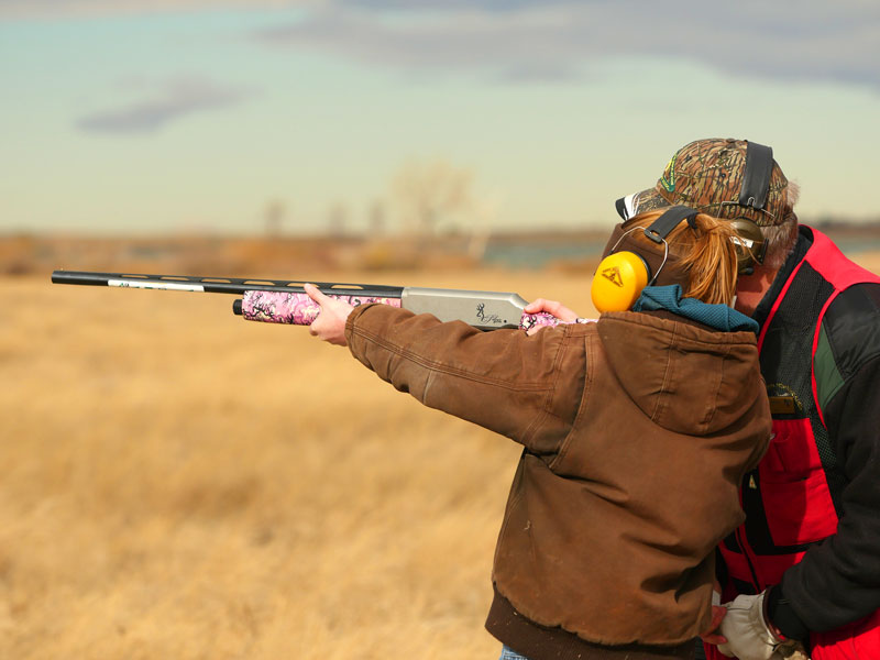Young girl learning to shoot a shotgun
