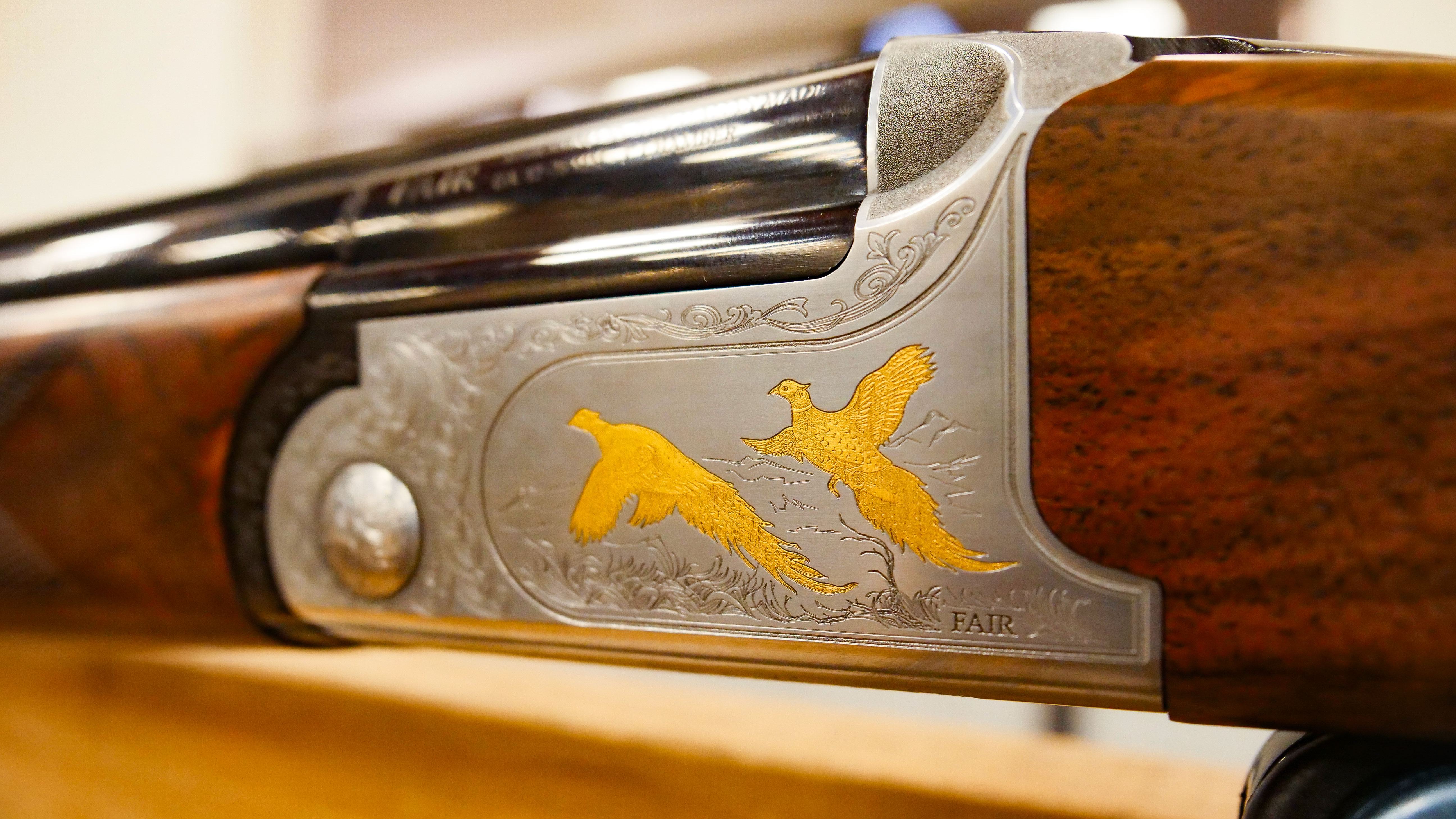 Shotgun with 2 gold pheasants flying on the stock of the gun