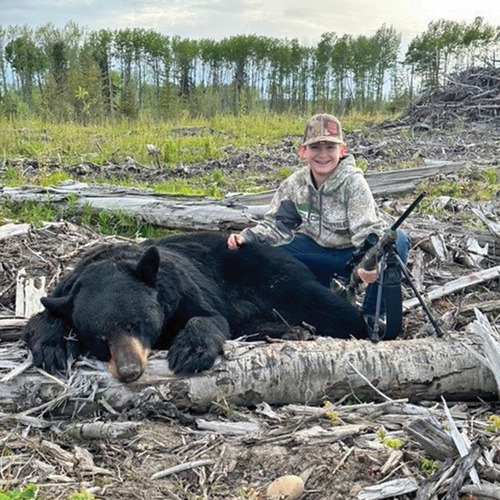 Hunter sits next to dead bear