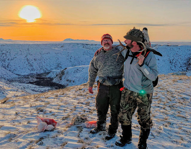 Dr. Foote and friend stand over landscape after field dressing a deer.