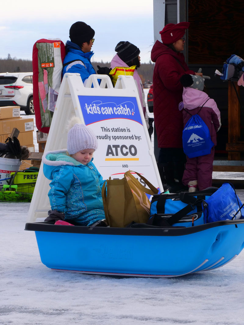 Kid on a sled on ice passing by the sponsor ATCO